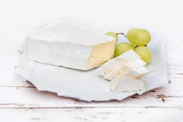 スライスと木の板に白い素朴なブドウの新鮮なブリーチーズ ブリーチーズ チーズの種類です カマンベール チーズ — ストック写真