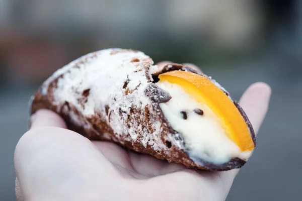 Cannoli op een hand met onscherpe achtergrond. — Stockfoto