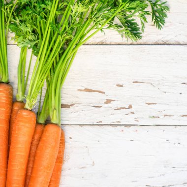 Birkaç havuç... Taze havuç yığın yeşil saplı. Rustik Beyaz ahşap zemin üzerinde çiğ havuç