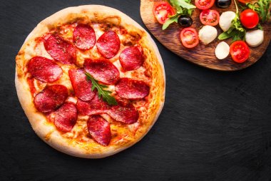 Siyah beton zemin üzerine İtalyan biberli pizza. Boşaltmak. Üstten Görünüm.