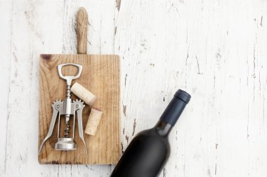 Bir şişe kırmızı şarap, tirbuşon ve rustik Beyaz ahşap zemin üzerinde şarap mantarlar