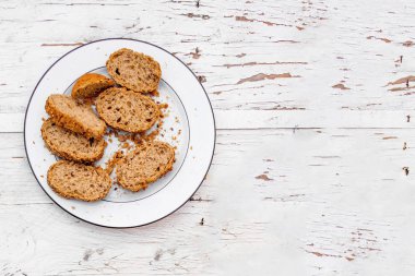 Rustik Beyaz ahşap zemin üzerinde beyaz tabakta tüm kepek ekmek taze dilim