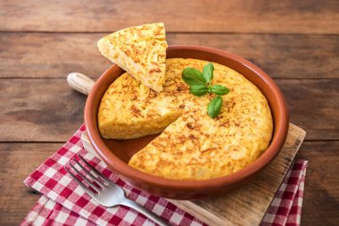 Spanish potato omelet called tortilla de patatas on a rustic wooden texture with a place for tex clipart
