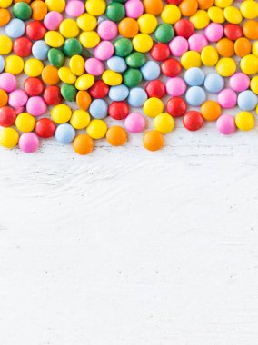 C ile beyaz rustik ahşap arka plan üzerinde renkli yuvarlak şekerler