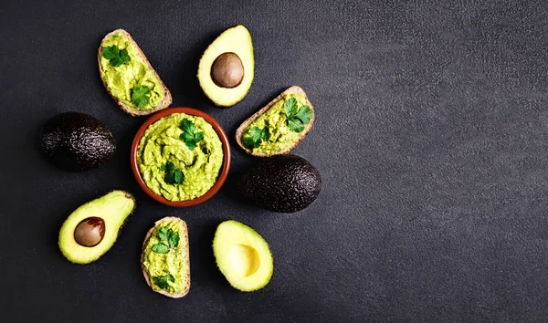 Avocado Met Guacamole Saus Een Kom Zwarte Achtergrond Bovenaanzicht Geheel — Stockfoto