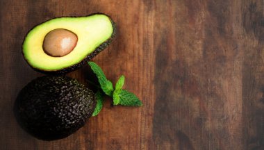 Koyu ahşap arka plan üzerinde yukarıdan avokado ve nane yaprakları