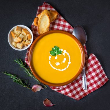 Siyah arka plan üzerine krema ve otlar ile kabak ve havuç çorbası Üstten Görünüm