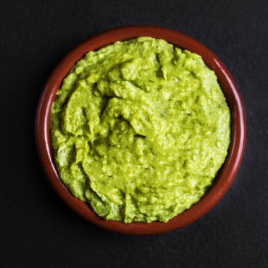 Top view of guacamole spread in clay bowl on black background clipart