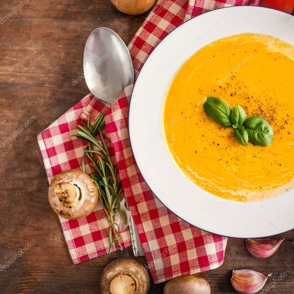 Close view of cream soup with pumpkin and carrot on wooden table