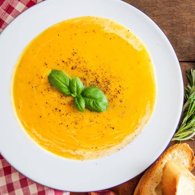 Kabak ve havuç ahşap rustik masa üzerinde kırmızı klasik damalı masa örtüsü üzerinde krem çorbası