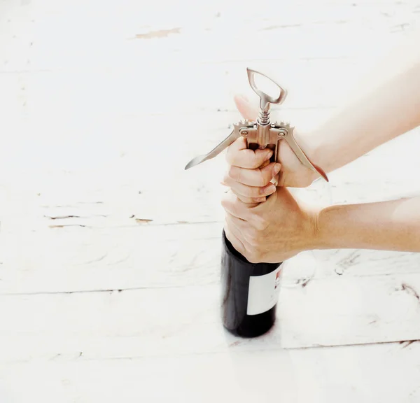 Штопор и бутылка вина на белой доске. Женщина открывает руку — стоковое фото