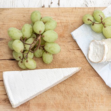 Beyaz ahşap üzerinde farklı peynir ve üzüm ile peynir tabağı