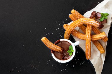 Siyah arka planda bir fincan sıcak çikolatalı Churros. üst yaşam