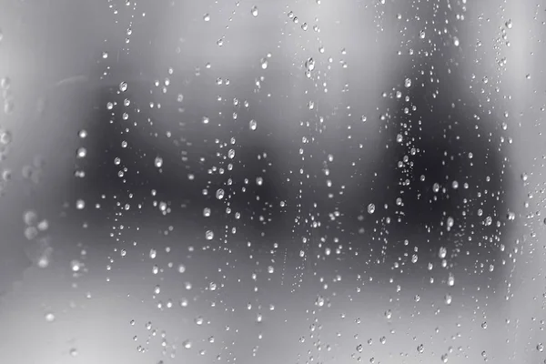 A água da chuva cai na janela clara. Padrão natural de gotas de chuva — Fotografia de Stock