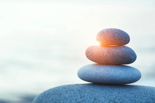 rock pebble pyramid, zen stones on sea beach at morning sunrise, meditation, spa, harmony, calm and balance concept, copy space