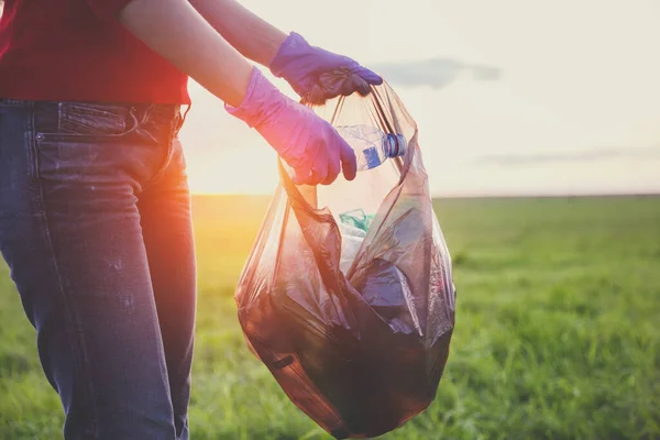 young volunteer woman collecting trash at sunset or sunrise light, earth nature  plastic pollution concept
