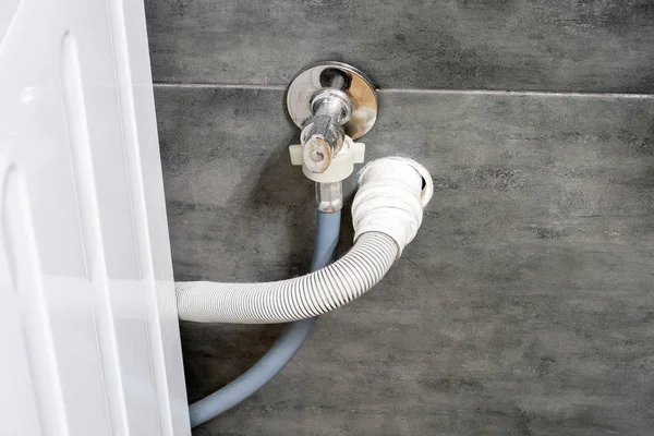 Çamaşır makinesi için kirli lavabo ve su hortumları gri betonla kaplı bir duvara çarpıyor. Rahat modern bir tuvalette tasarım seçenekleri