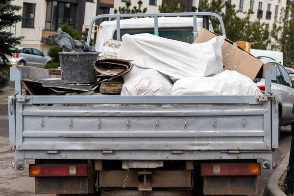 Çöp, torba, mukavva, inşaat atığı ve dikiz aynasıyla dolu açık bir kamyonet. Binaların onarımından ve inşaatından sonra çöp toplama