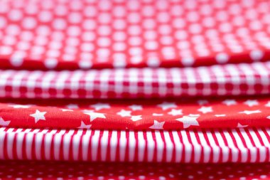 Horizontal textural background of five types of red and white cotton fabric with different prints. Selective focus. Closeup view