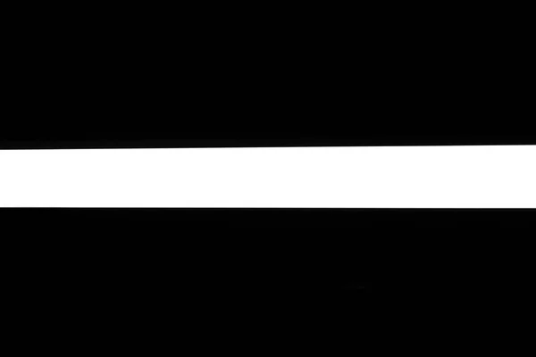 Modern white neon wall or ceiling lamp in the form of a long stripe in a dark room. Horizontal abstract geometric shape and line on a black background — 스톡 사진