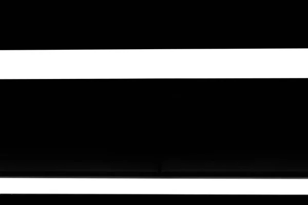 Two modern white neon wall or ceiling lamps in the form of a long stripe in a dark room. Horizontal abstract geometric shape and line on a black background — 스톡 사진
