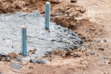 Bir aydınlatma kolonu ya da reklam panosu için beton dökme ve çapa hazırlama. Toprakta iki demir cıvatalı beton bir temel var. Seçici odaklanma. Yakın görünüm