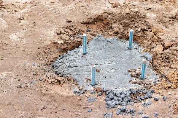 Bir aydınlatma kolonu ya da reklam panosu için beton dökme ve çapa hazırlama. Toprakta dört demir cıvatalı beton bir temel var. Seçici odak