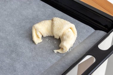 Kruvasan, parşömen kağıdına şeker serpiştirilmiş süzme peynir hamurundan pişirmek için hazırlandı. Fırına koymadan önce tatlı simit. Ekşi simit yapma süreci