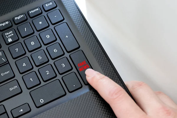 黑色笔记本电脑的键盘角落 一个女性的手指点击一个假的新闻按钮 在互联网上传播假新闻和信息的概念 — 图库照片