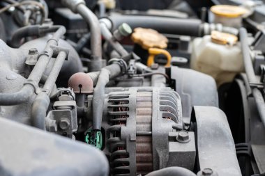 Alternatör. Açık kaputun altındaki dört silindirli motor kompartımanının tozlu detayları. Yakın kenar görünümü