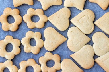 Pişmiş kurabiye kalp şeklinde ve fırından yeni çıkarılmış parşömen kağıdıyla fırında çiçek. Kahvaltıda atıştırmalık çay. Seçici odaklanma. Yakın görünüm