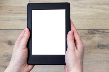 Bulanık ahşap döşeme zeminine karşı kadın ellerinde beyaz bir ekranı olan modern siyah elektronik bir kitap. Model tableti kapat