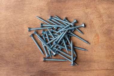 Ahşap arka planda metal vidalar yığını
