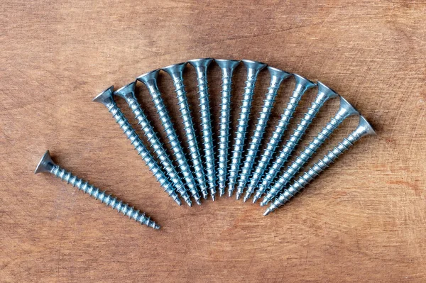 Pile Metal Screws Fan One Lies Separately Wooden Background Closeup — Stock Photo, Image