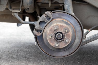 Lastik dükkanında fren diski olan paslı arka araba tekerleği. Lastik servis merkezini değiştirirken tekerleksiz araba. Yakın görünüm