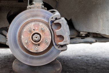 Lastik dükkanında fren diski olan paslı arka araba tekerleği. Lastik servis merkezini değiştirirken tekerleksiz araba. Yakın görünüm