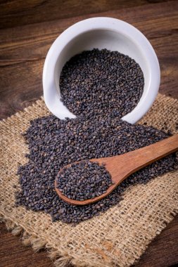 Heap of black Sesame (close-up shot) on wooden background clipart