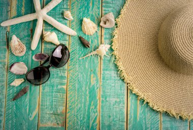 Deniz kabuklarını hasır şapka ve sunglass yeşil ahşap tahta üzerinde