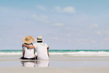 Genç aile bir deniz sıcak kum üzerinde oturan ve bir yer arıyorum