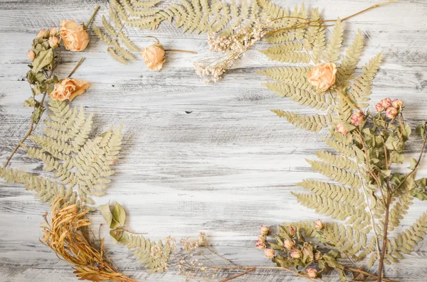 Rahmen mit Farnblättern, Rosen und Zweigen auf Holzgrund — Stockfoto