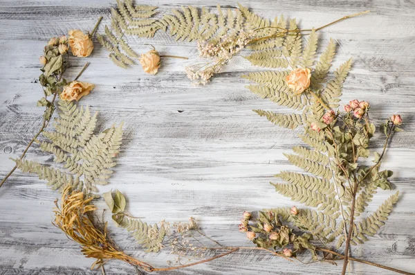 Frame met fern bladeren, rozen en takken op houten achtergrond — Stockfoto
