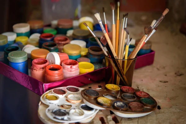Artists brushes, paint cans and palette close-up