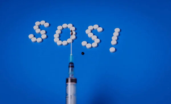 Mavi arka plandaki haplardan şırınga ve Sos. Bağımlılık kavramı ve HIV önleme