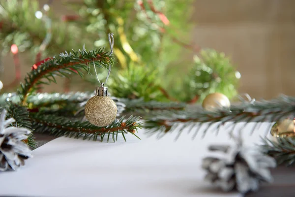 Christmas, decoration on a white table background with a blank white sheet. New Year\'s pine cones and golden Christmas balls. Place for text.
