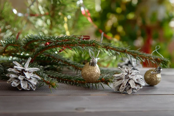 Noel, ahşap bir masanın üzerindeki süs. Noel kozalakları ve altın Noel topları.