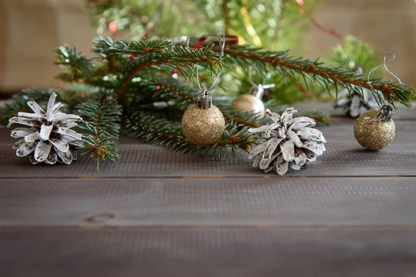 Noel, ahşap bir masanın üzerindeki süs. Noel kozalakları ve altın Noel topları.