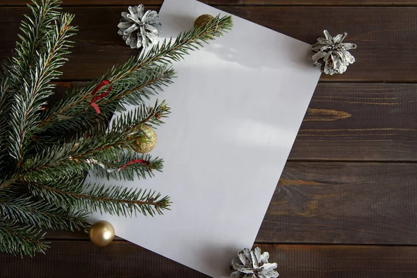 Christmas, decoration on a white table background with a blank white sheet. New Year\'s pine cones and golden Christmas balls. Place for text.
