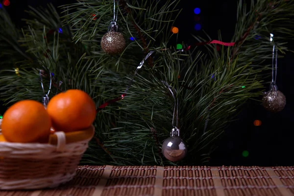  Noel, ahşap bir masanın üzerindeki süs. Hasır sepette Noel mandalinaları, koniler ve altın Noel topları