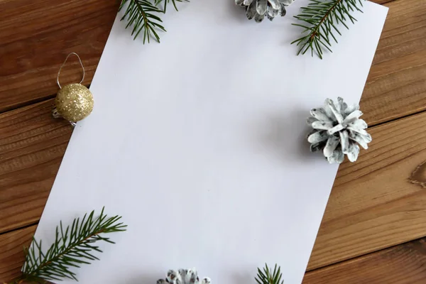Christmas, decoration on a white table background with a blank white sheet. New Year's pine cones and golden Christmas balls. Place for text.
