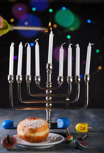 Židovská dovolená Chanuka pozadí. Tradičním pokrmem jsou sladké koblihy. Chanuka stůl nastavení svícen se svíčkami a točící se vrcholy na modrém pozadí. Zapalování svíček Chanuky. Kopírovat prostor — Stock fotografie
